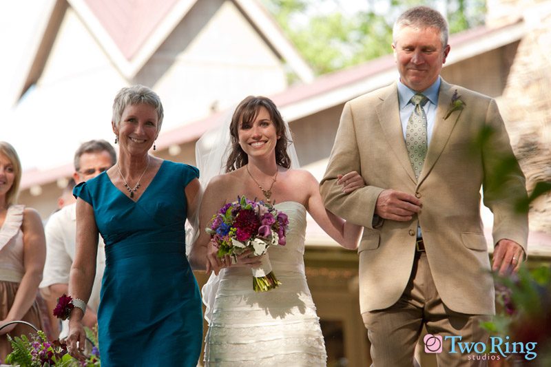 Bride walks down aisle with mother and father