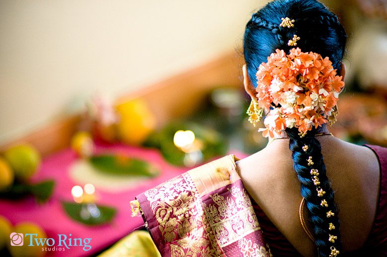 Indian bride faces away showing off her flower adorned, braided hair.